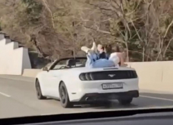Фотосессию на багажнике движущегося кабриолета устроила девушка в Сочи